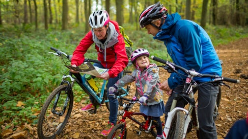 Family on a bike ride in autumnal woods, looking at a map